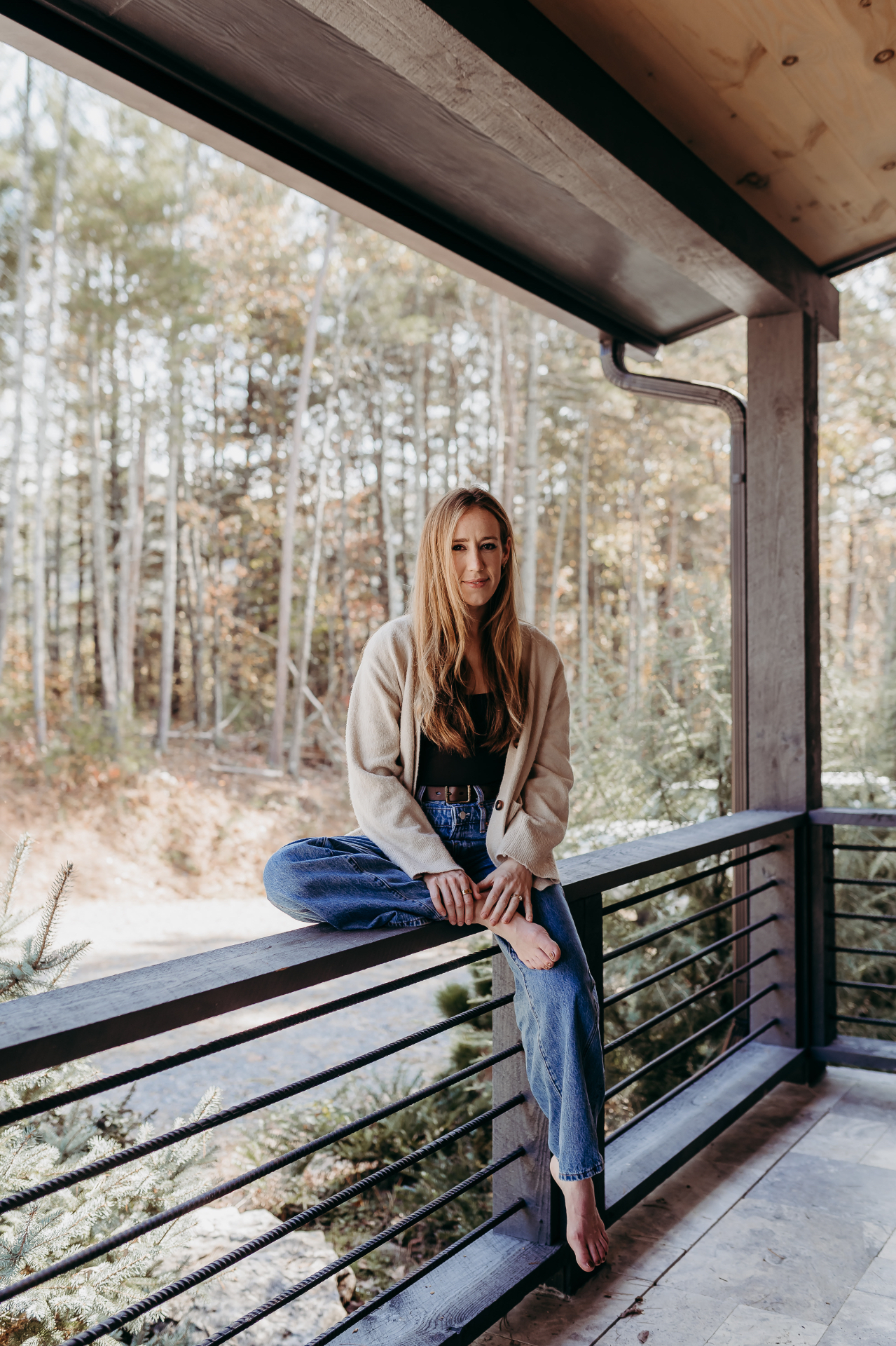Molly sitting on a wooden porch railing surrounded by trees